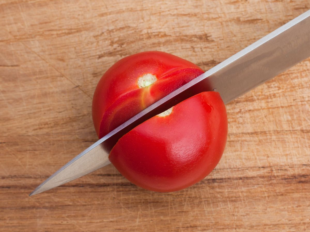 牛刀でトマトを薄くスライスする様子。熟したトマトも潰さず切れる鋭い切れ味