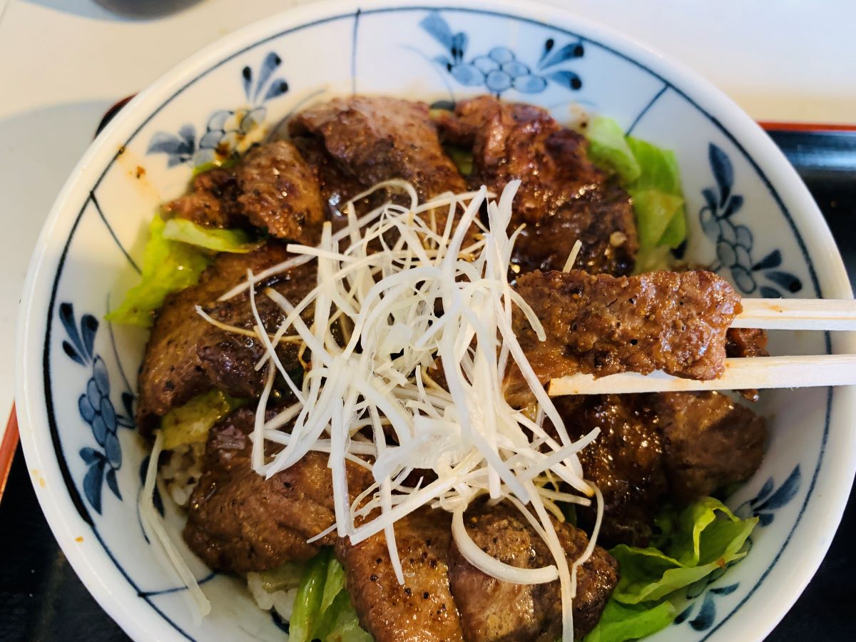 築地どんぶり市場の名物「まぐろほほ肉ステーキ丼」。肉厚なマグロ希少部位を香ばしく焼き上げた、ジューシーな絶品丼