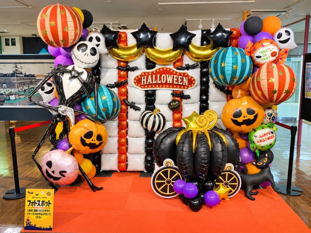 築地おもしろ市場のハロウィン2026フォトスポット。かぼちゃやおばけの風船、黒いかぼちゃの馬車を飾った撮影コーナー